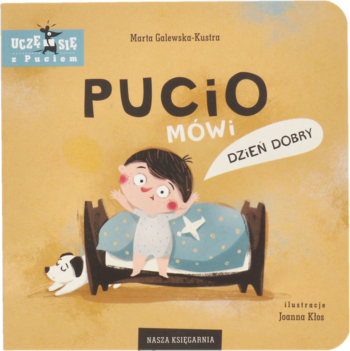Pucio Mówi Dzień Dobry, beżowa okładka książki dla dzieci. Chłopiec w piżamie w łóżku, pies obok. Widok z przodu.