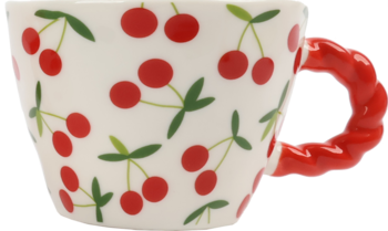 Biały kubek ceramiczny w czerwone wisienki z zielonymi listkami, z rączką w kształcie skręconego sznurka, widok z boku.
