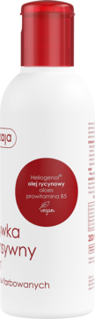 Biała butelka aktywnego preparatu do włosów farbowanych z czerwoną nakrętką, widok z boku, etykieta z Heliogenolem.