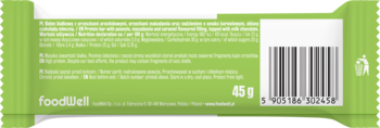 Tył zielonego opakowania batona proteinowego FoodWell o smaku orzeszków macadamia i karmelu, z kodem kreskowym i tekstem.