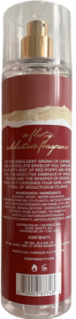 Tył przezroczystej butelki mgiełki zapachowej. Czerwona etykieta ze złotymi napisami, w tym 'a flirty addictive fragrance'.