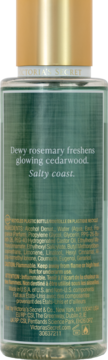 Tył zielonej butelki mgiełki Victoria's Secret Cedar Breeze ze złotą nakrętką. Widoczny tekst zapachowy: 'rosemary freshens cedarwood, salty coast'.