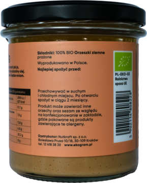 Tył szklanego słoika Ekogram BIO pasty orzechowej, pomarańczowa etykieta ze składnikami i logo BIO.