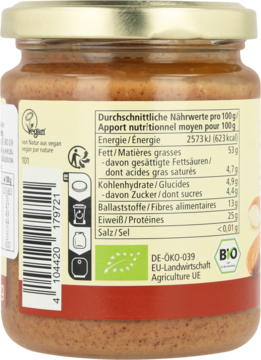 Tył słoika pasty migdałowej Alnatura z tabelą wartości odżywczych, logo Vegan i Bio na beżowej etykiecie.