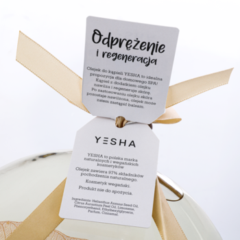 Yesha olejek do kąpieli, zbliżenie na dwie białe etykiety z napisem "Odprężenie i regeneracja", związane złotą wstążką.