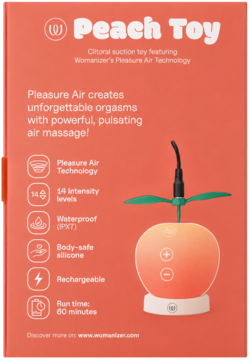 Womanizer Peach Toy, różowo-pomarańczowy, w kształcie brzoskwini, z listkami, na tle otwartego opakowania.