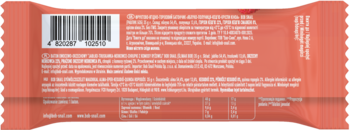 Tył pomarańczowego opakowania batonika energetycznego z kodem kreskowym i etykietą składu. Widok z bliska.