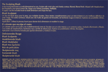 Biały tekst opisujący róż do policzków Sculpting Blush w kilku językach na ciemnoniebieskim tle.