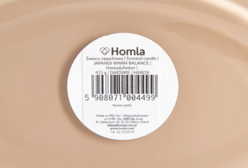 Zbliżenie na okrągłą białą etykietę świecy zapachowej Homla Japandi Warm Balance Honey&Amber 415g z kodem.