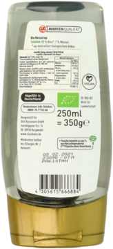 Tył butelki organicznego syropu ryżowego 250ml, z etykietą zawierającą skład i datę ważności, butelka z recyklingu.