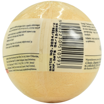 Jasnobeżowa kula do kąpieli, owinięta w folię. Widok z boku etykiety z kodem kreskowym i datą ważności.