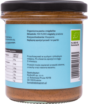 Zbliżenie na tył słoika z ekologiczną pastą z prażonych migdałów, niebieska etykieta z danymi i BIO certyfikatem.