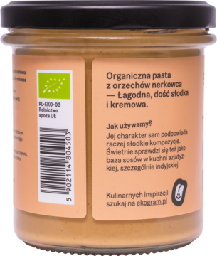 Tył słoika z ekologiczną pastą z orzechów nerkowca. Widoczny opis: łagodna, słodka, kremowa oraz bio certyfikat.