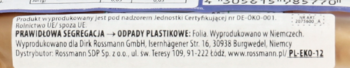 Biała etykieta na opakowaniu batonika enerBio, z danymi producenta Dirk Rossmann GmbH, widok z bliska.