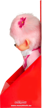 Różowa pluszowa lalka Monchhichi w czerwonym pudełku, z różowym kwiatkiem na głowie i białym kołnierzykiem, widok z boku.