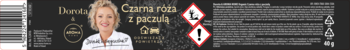 Etykieta odświeżacza powietrza o zapachu czarnych róż i paczuli, z uśmiechniętą kobietą i piktogramami zagrożeń.
