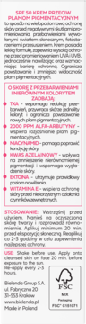 Tył białego opakowania kremu SPF 50 przeciw plamom, z opisem działania, składnikami aktywnymi i instrukcją użycia.