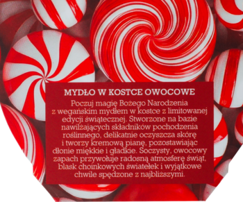 Wegańskie mydło owocowe w kostce. Czerwona etykieta na tle świątecznych cukierków w paski.