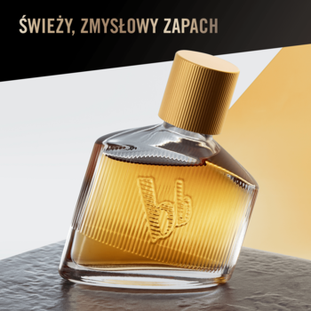 Złota woda toaletowa bruno banani Man’s Best w pochylonym flakonie z logo bb na tle czerni i złota.