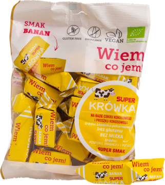Żółte wegańskie krówki bananowe Super Krówka w przezroczystej torebce, z napisami 'Wiem co jem!'.