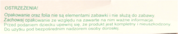 Zbliżenie na jasnozieloną etykietę z ostrzeżeniami bezpieczeństwa dla produktu puzzle Odkrywam koło, tekst rozmazany.