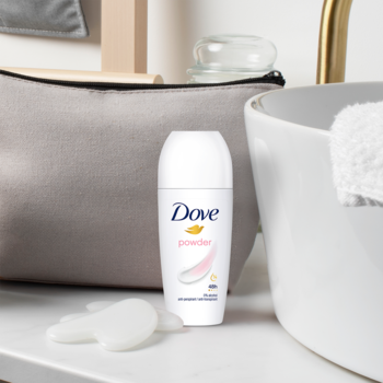 Biały antyperspirant Dove Powder roll-on 48h z różowym akcentem, widok z przodu na łazienkowej umywalce.