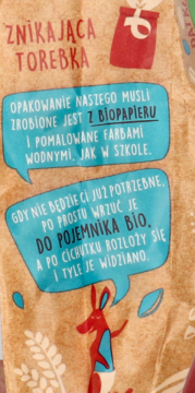 Brązowe opakowanie musli potrójnie orzechowego z biopapieru. Informacje o biodegradowalności w niebieskich dymkach, czerwony królik.