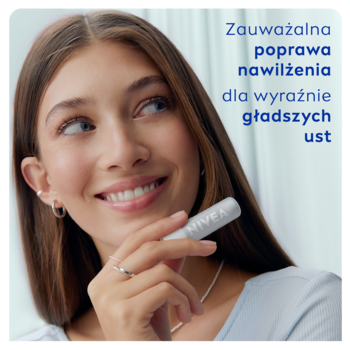Kobieta z brązowymi włosami trzyma białą pomadkę NIVEA Hyaluron, wskazując na jej właściwości nawilżające usta.