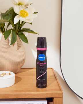 NIVEA Extreme Hold lakier do włosów 250ml, czarna puszka z różową nakrętką, pionowo na drewnianej komodzie.