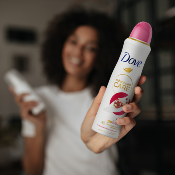 Antyperspirant Dove Advanced Care Granat 72h, biały spray z różową nakrętką, trzymany przez kobietę.