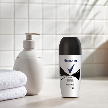 Antyperspirant Rexona Invisible Black & White w kulce, biało-czarny, na tle łazienki z ręcznikami.