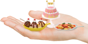 Zestaw miniaturowych zabawek jedzenia: banana split, różowy tort piętrowy i danie z makaronu, trzymane w dłoni.