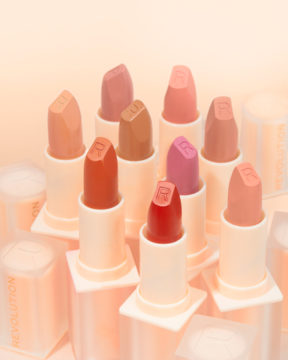 Revolution Lip Allure Soft Satin Lipstick: dziewięć satynowych pomadek nude/róż/czerwień, ustawionych pionowo, z logo R.