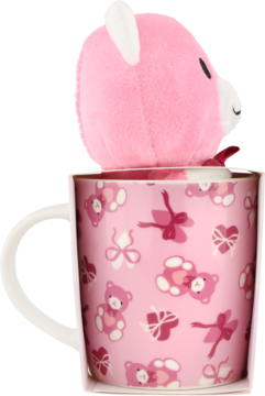 Eloy różowy kubek z misiami i kokardkami, a z niego wystaje głowa różowego pluszaka. Widok z boku.