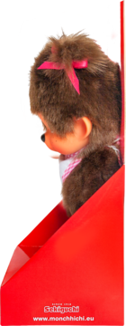 Monchhichi, brązowa pluszowa małpka z różową kokardą, bokiem w czerwonym pudełku z logo producenta.