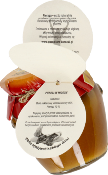 Pierzga w miodzie w szklanym słoiku z unikatową, beżową etykietą produktową w kształcie wachlarza, widok z przodu.
