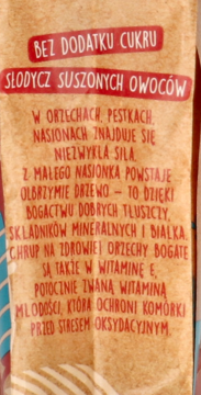 Tył opakowania musli potrójnie orzechowego na beżowym tle, z czerwonymi napisami o braku cukru.