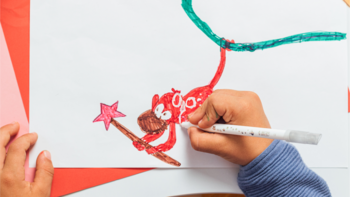 Dziecięca ręka rysuje flamastrem Bic Kids czerwonego smoka z różdżką na białej kartce, pokazując magiczne efekty.