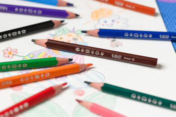 Kolorowe kredki trójkątne XL leżące na papierze z rysunkiem dziecka. Pomagają w nauce prawidłowego chwytu.