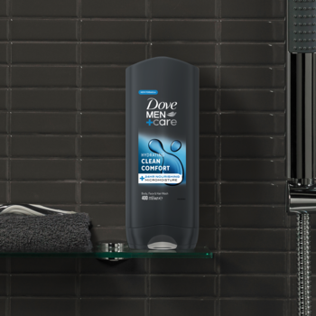 Męski żel pod prysznic Dove Men+Care Clean Comfort, ciemna butelka 400 ml na szklanej półce w łazience.