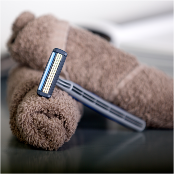 Golarka męska BIC 3 Flex, trójostrzowa, z niebieskim uchwytem, oparta na zwiniętym, brązowym ręczniku.