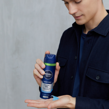 NIVEA MEN Protect & Care Ochronny Żel do golenia, wyciskany z niebiesko-zielonej butelki do dłoni mężczyzny.