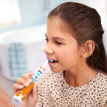 Dziewczynka używa pomarańczowej szczoteczki sonicznej Philips Sonicare For Kids z motywem zwierzęcym, widok z boku.