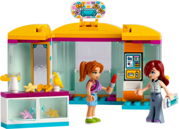 Zestaw Lego Friends Mały sklep z akcesoriami: żółto-różowy budynek, dwie lalki, lustro, kasa. Ujęcie z przodu.