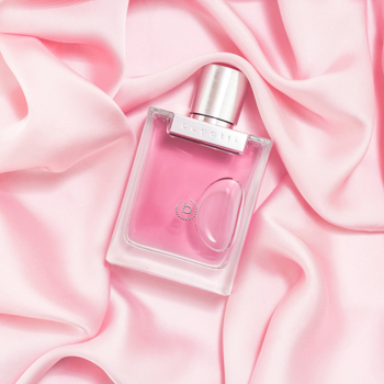 Damskie perfumy Bugatti Bella Donna ROSA, różowy płyn w prostokątnym flakonie na drapowanym różowym jedwabiu.