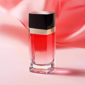 Bugatti Eleganza Rossa, słodkie damskie perfumy. Szklana butelka z gradientem czerwieni, czarna nakrętka, na różowym jedwabiu.