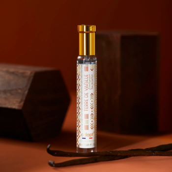 Adopt Terre de Vanille, mała butelka perfum z zlotą nakrętką i etykietą. Suszone laski wanilii na brązowym tle.