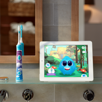 Interaktywna szczoteczka Philips Sonicare For Kids, biała z niebieskimi końcówkami, obok tablet z Sparkly.