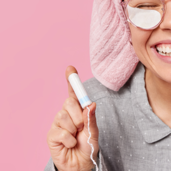 Biały tampon Joni Teens bez aplikatora, trzymany w dłoni przez uśmiechniętą kobietę na różowym tle.