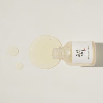 Beauty of Joseon Glow Serum z niacynamidem i propolisem, wylane obok leżącej butelki na jasnym tle.